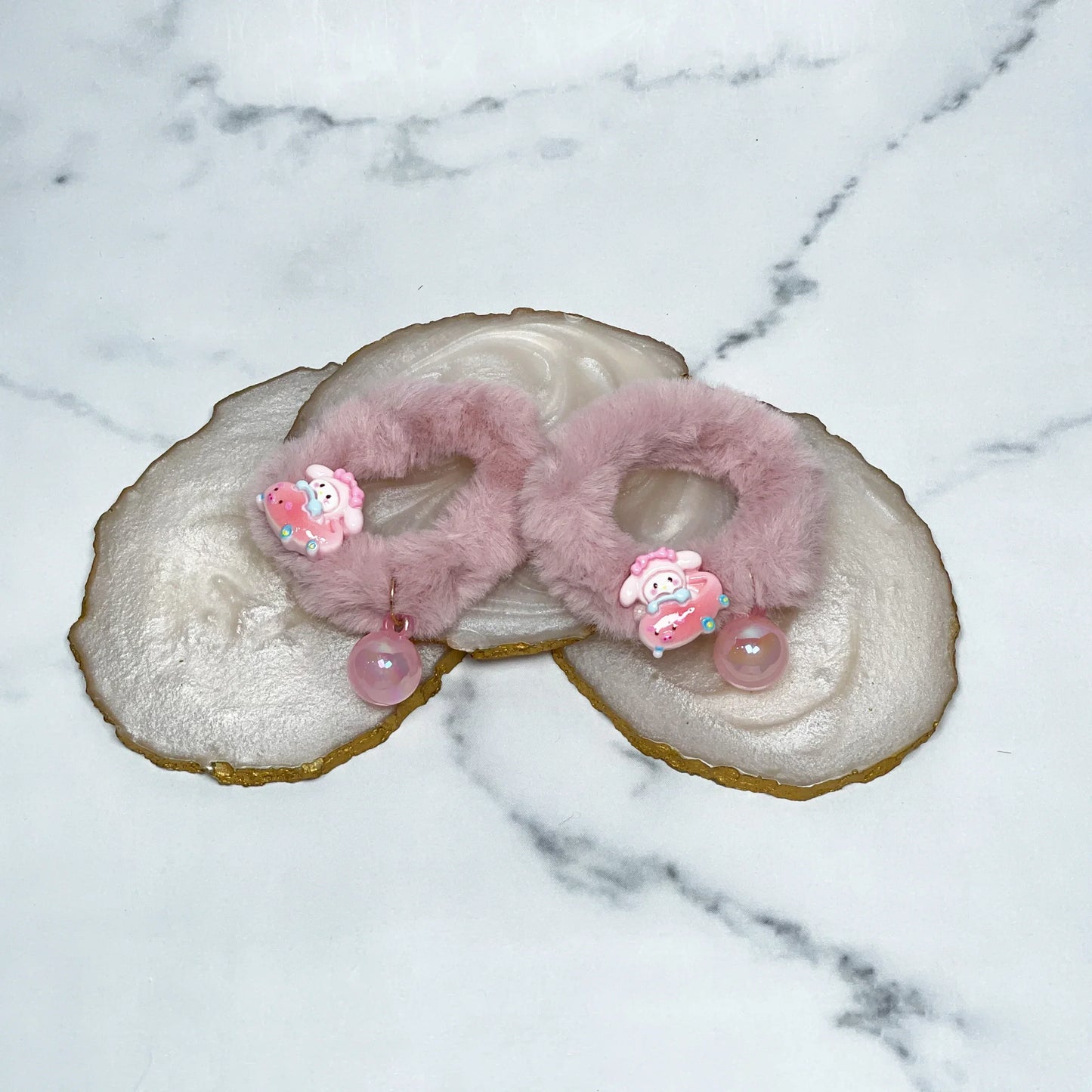 Pink kids furry hair ties with cute bear charms and dangling beads on marble background