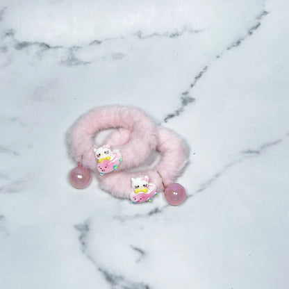 Pink kids furry hair ties with cute cat and donut charms on a marble background