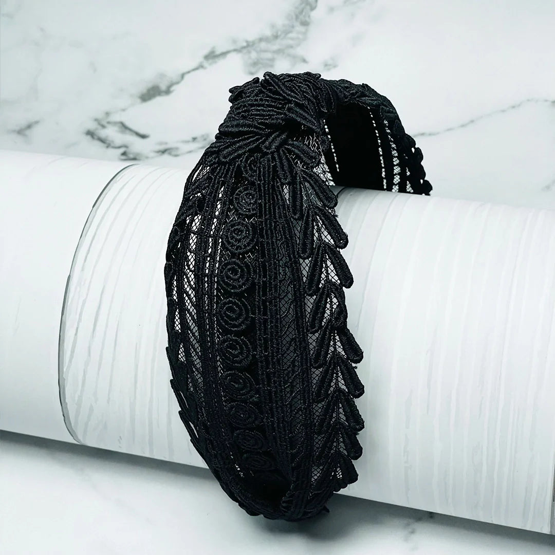 Black knotted hairbands with intricate lace design displayed on white textured surface