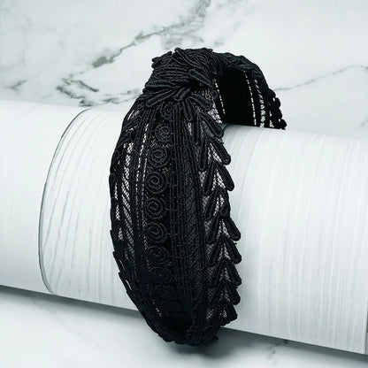 Black knotted hairbands with intricate lace design displayed on white textured surface