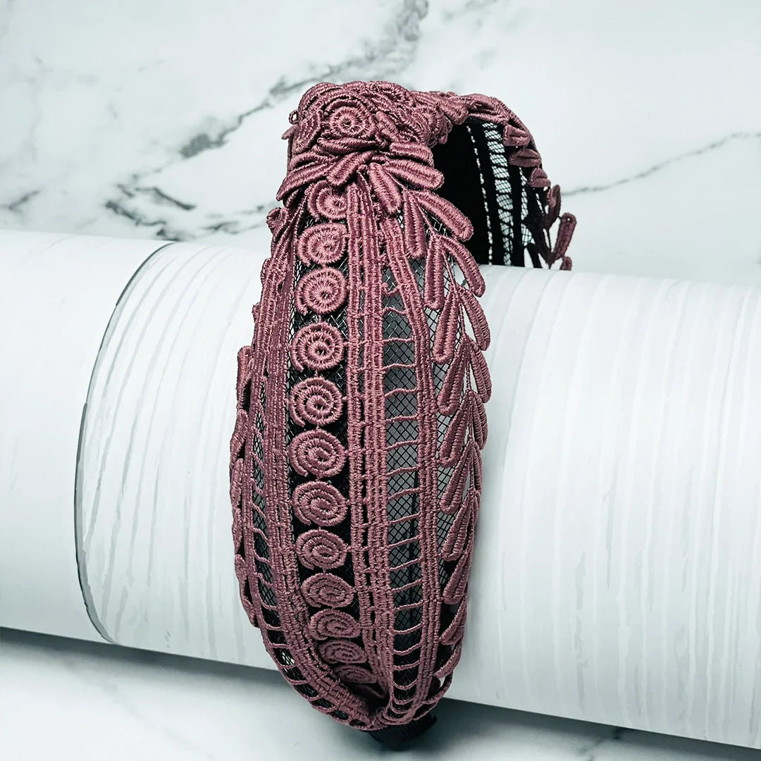 Pink intricate knotted hairbands with detailed embroidery displayed on a white surface