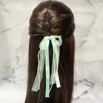 Lace satin pearl hair ties in light green tied on dark brown hair with decorative ribbons
