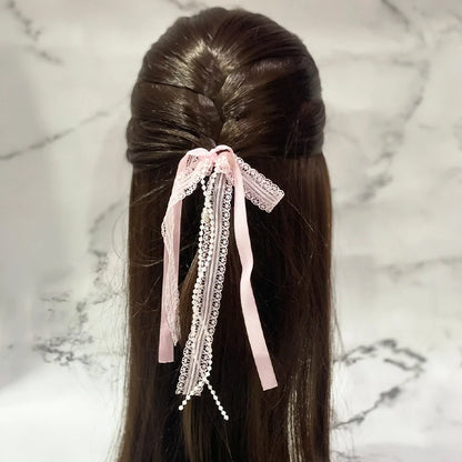 Pink lace satin pearl hair ties styled on long brown hair against a marble background