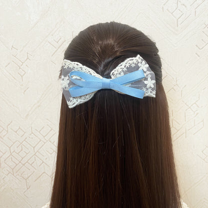 Lacy Bows with Ribbon in blue and white on long brown hair against textured wall