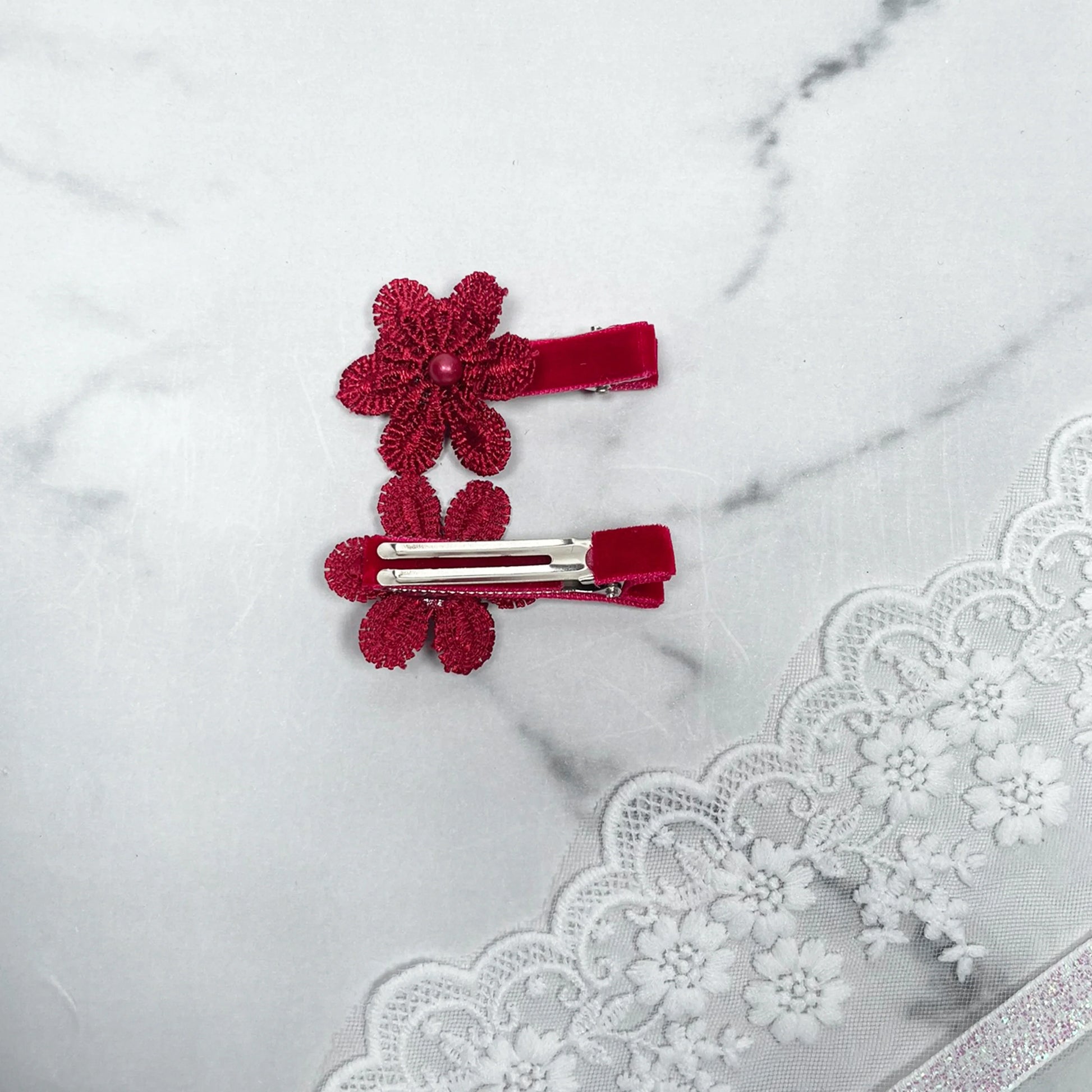 Lacy Flower Alligator Hair Pins with Beads in red placed on a marble surface with lace fabric