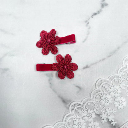 Pair of Lacy Flower Alligator Hair Pins with Beads in red on a marble surface with lace fabric