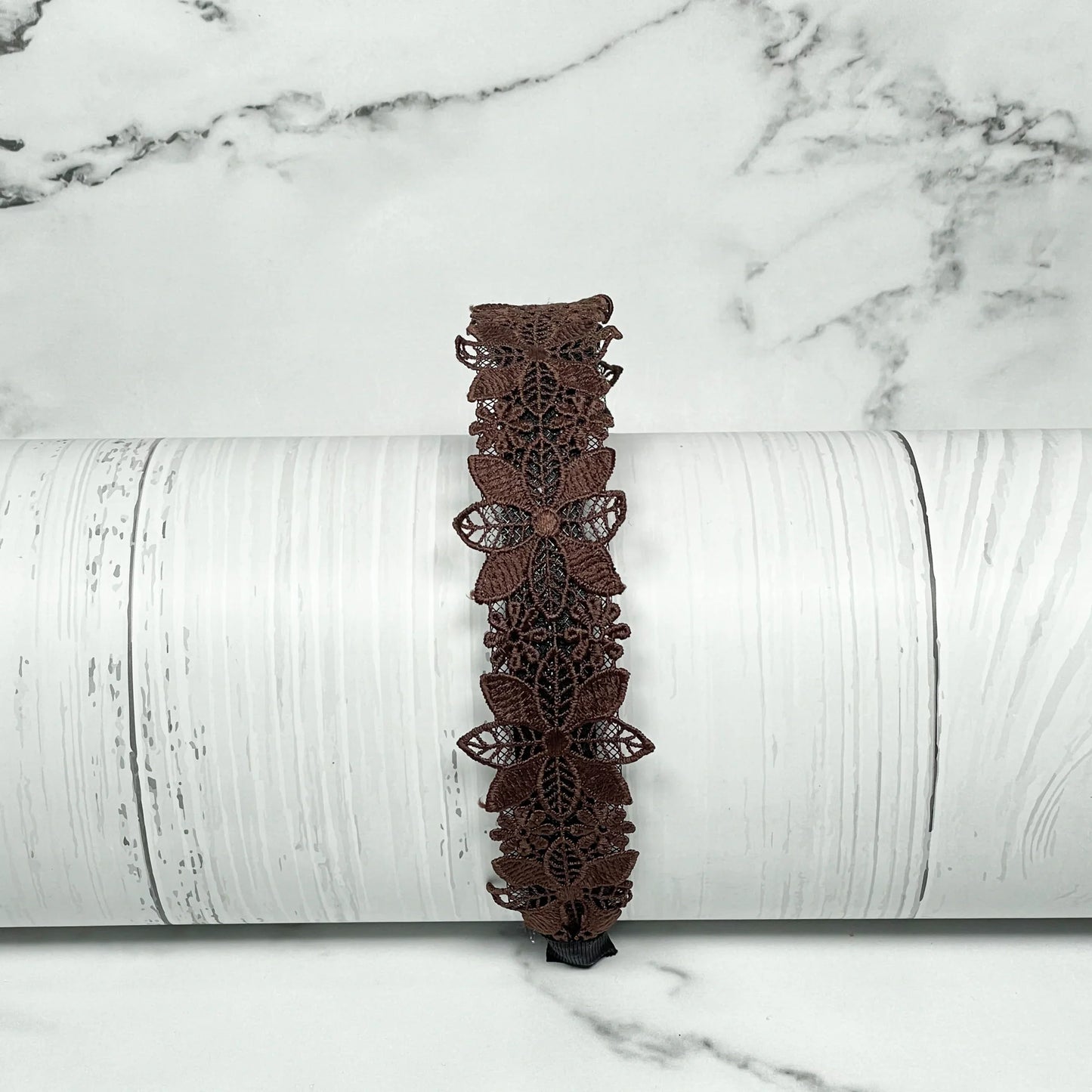 Brown medium broad colored hair bands with butterfly lace design displayed on white wooden background