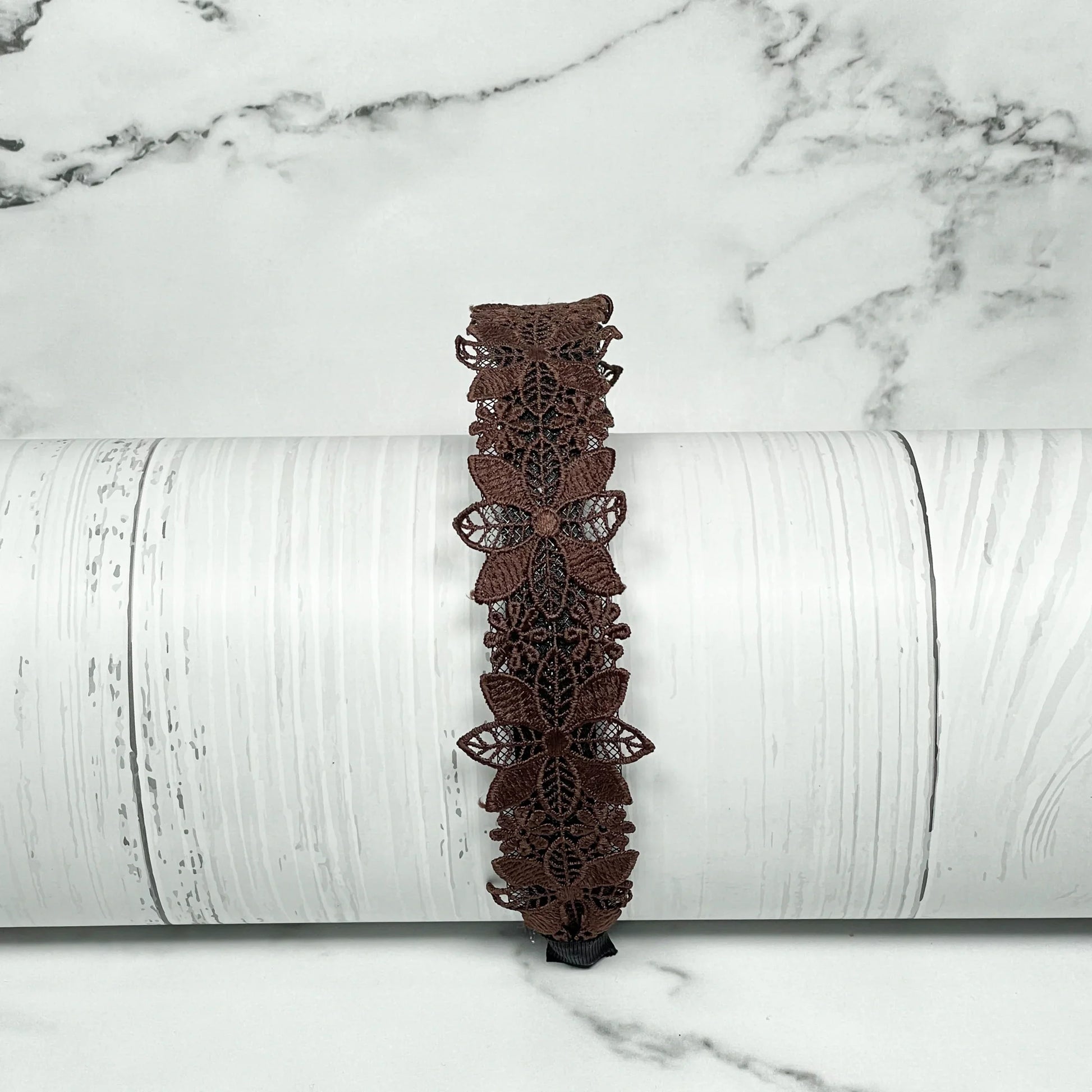 Brown medium broad colored hair bands with butterfly lace design displayed on white wooden background