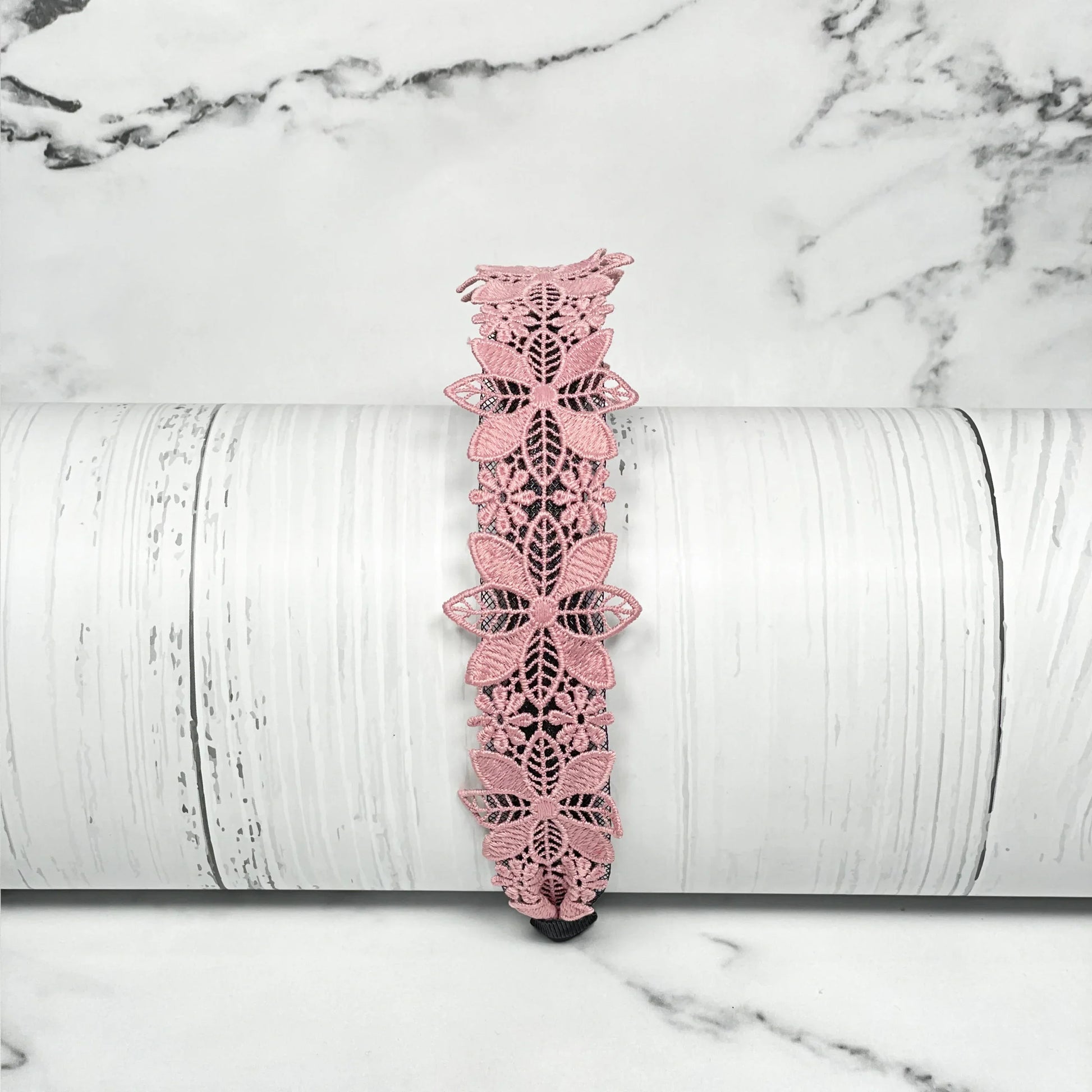 Medium broad colored hair bands in pink floral lace design displayed on white wooden surface