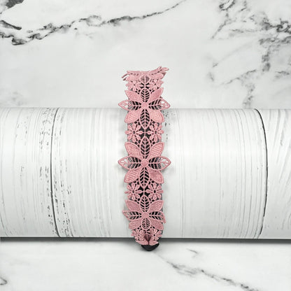 Medium broad colored hair bands in pink floral lace design displayed on white wooden surface
