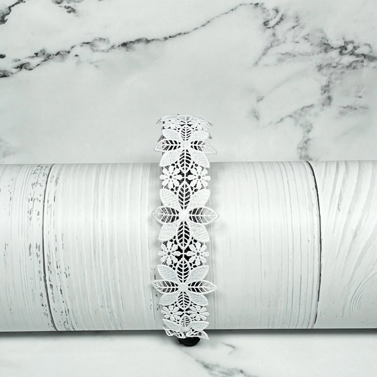White lace medium broad colored hair bands with floral design displayed on wooden surface
