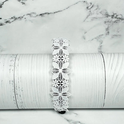 White lace medium broad colored hair bands with floral design displayed on wooden surface