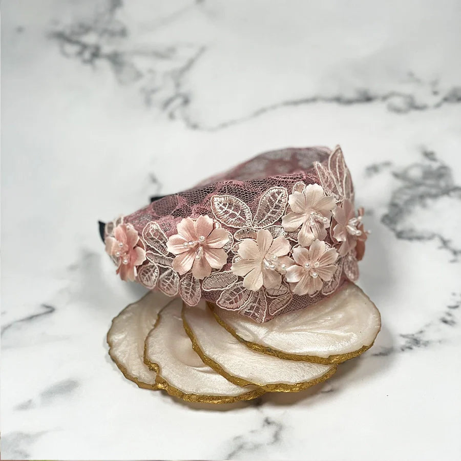 Pink mesh broad hairband decorated with 3D floral appliques placed on marble background