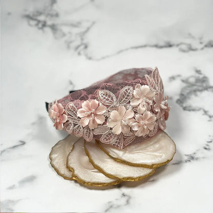 Pink mesh broad hairband decorated with 3D floral appliques placed on marble background