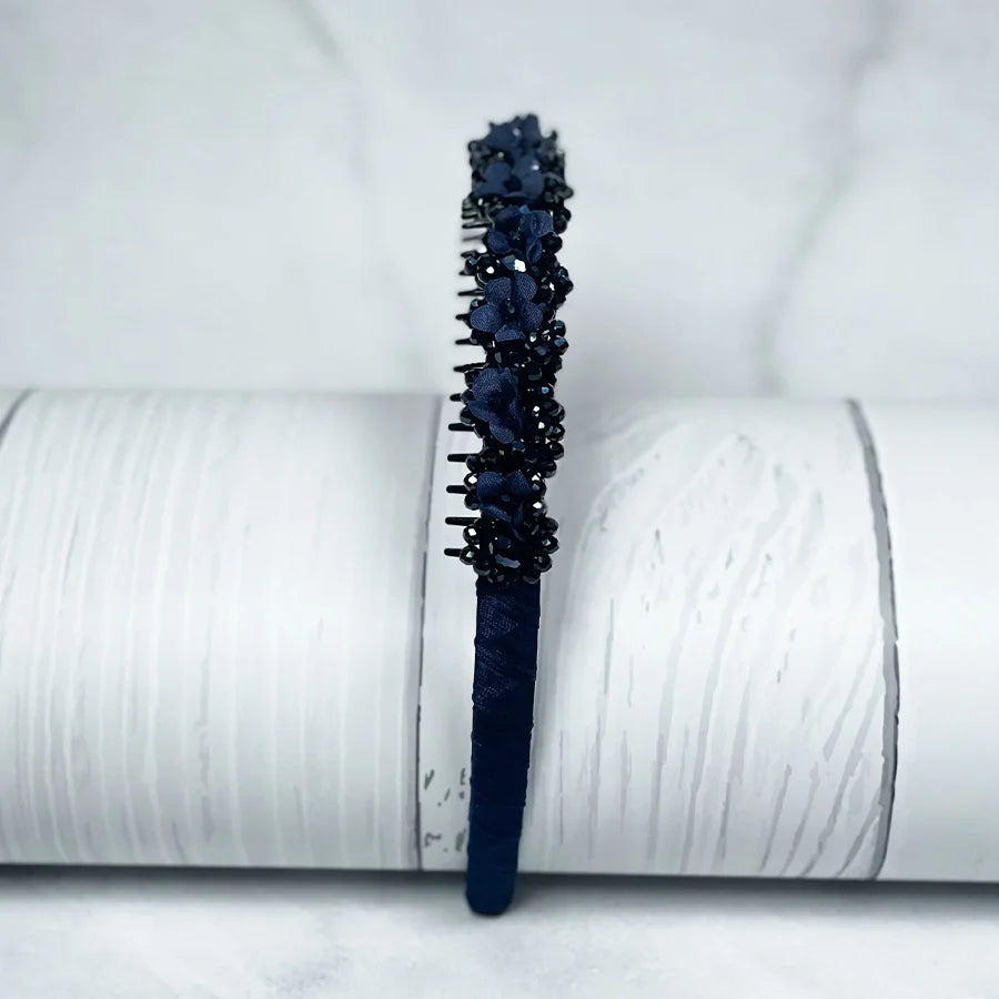 Dark blue embellished headbands for women with floral and bead decorations on a textured white background