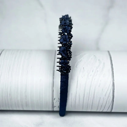 Dark blue embellished headbands for women with floral and bead decorations on a textured white background