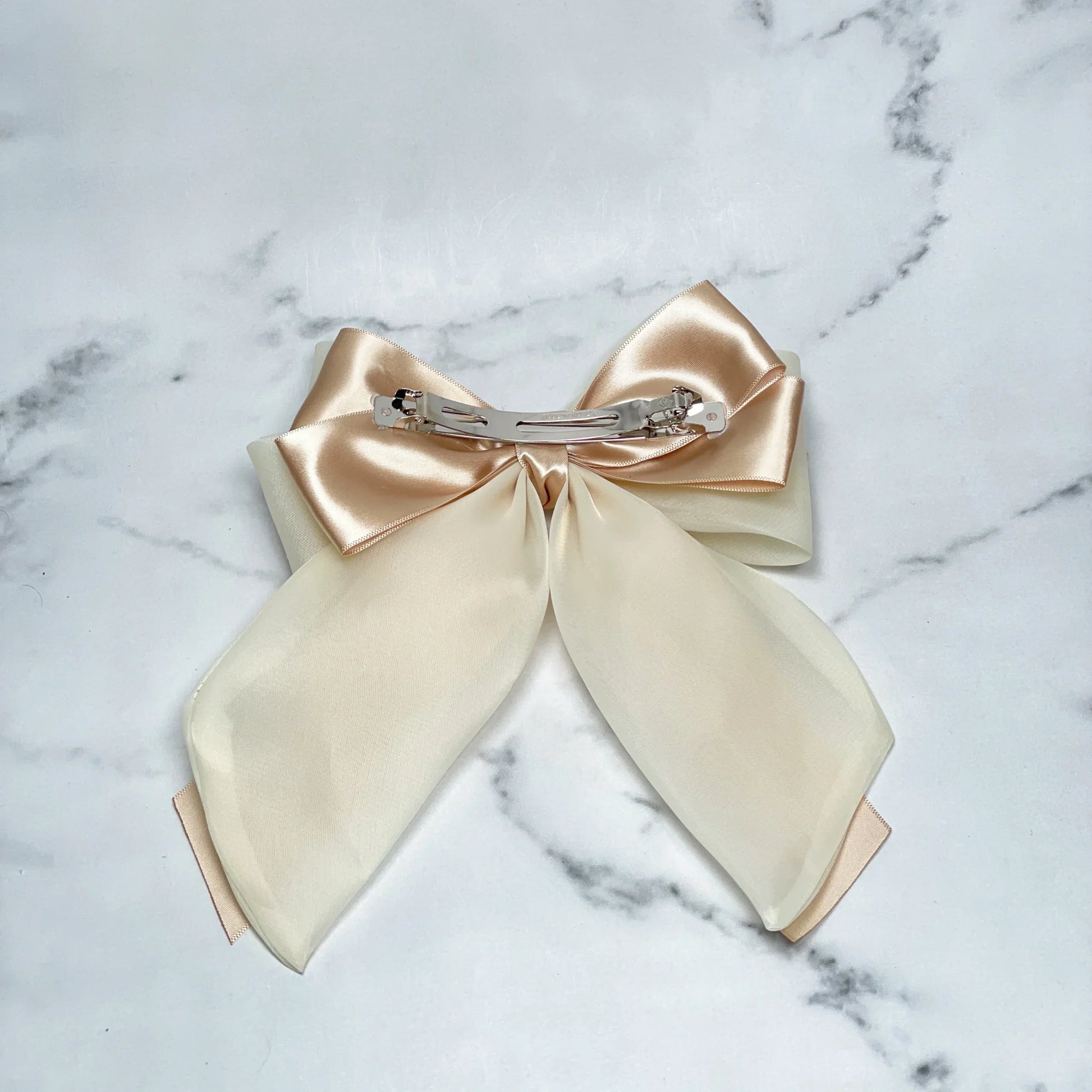 Organza and Satin Bow Clips in soft beige and cream colors with metal clip on marble background