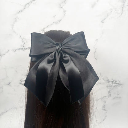 Black Organza and Satin Bow Clips worn on long brown hair against a marble background