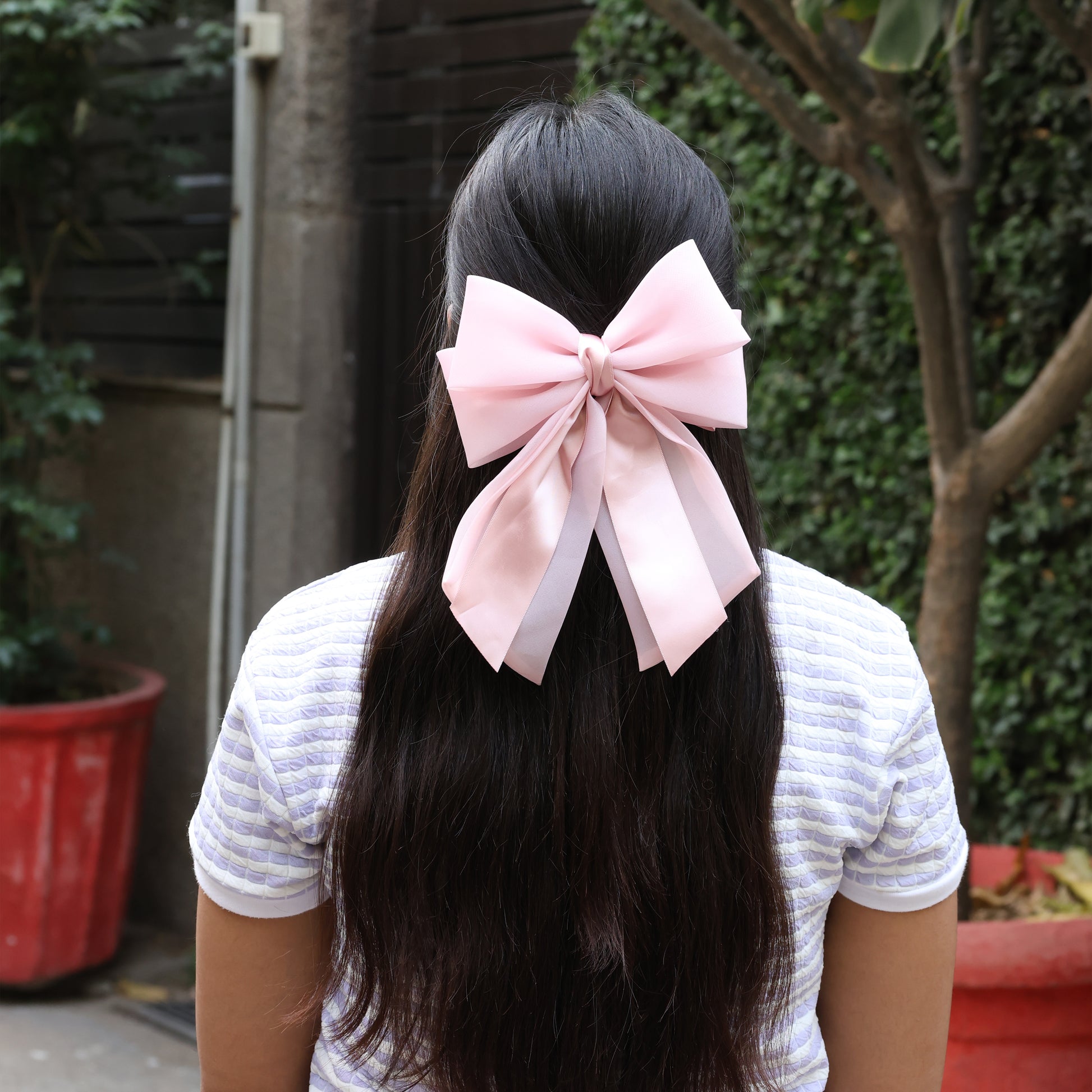 Pink Organza and Satin Bow Clips worn on long dark hair with white striped shirt outdoor background