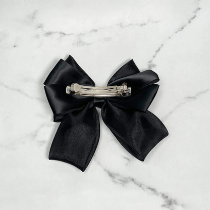 Black organza satin bow hair clips with metal clasp on marble background