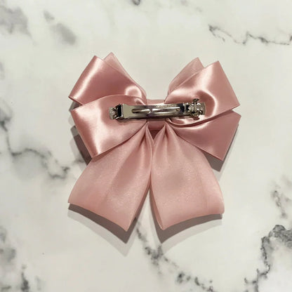 Pink organza satin bow hair clips with metal clip back on a white marble surface