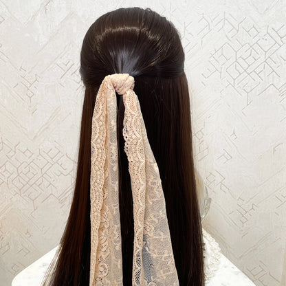 Bella Luxe peach lacy hair scarf tied in long dark hair with intricate lace pattern