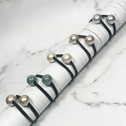 Colorful pearl bead hair ties displayed on white cylindrical holder with various pearl shades