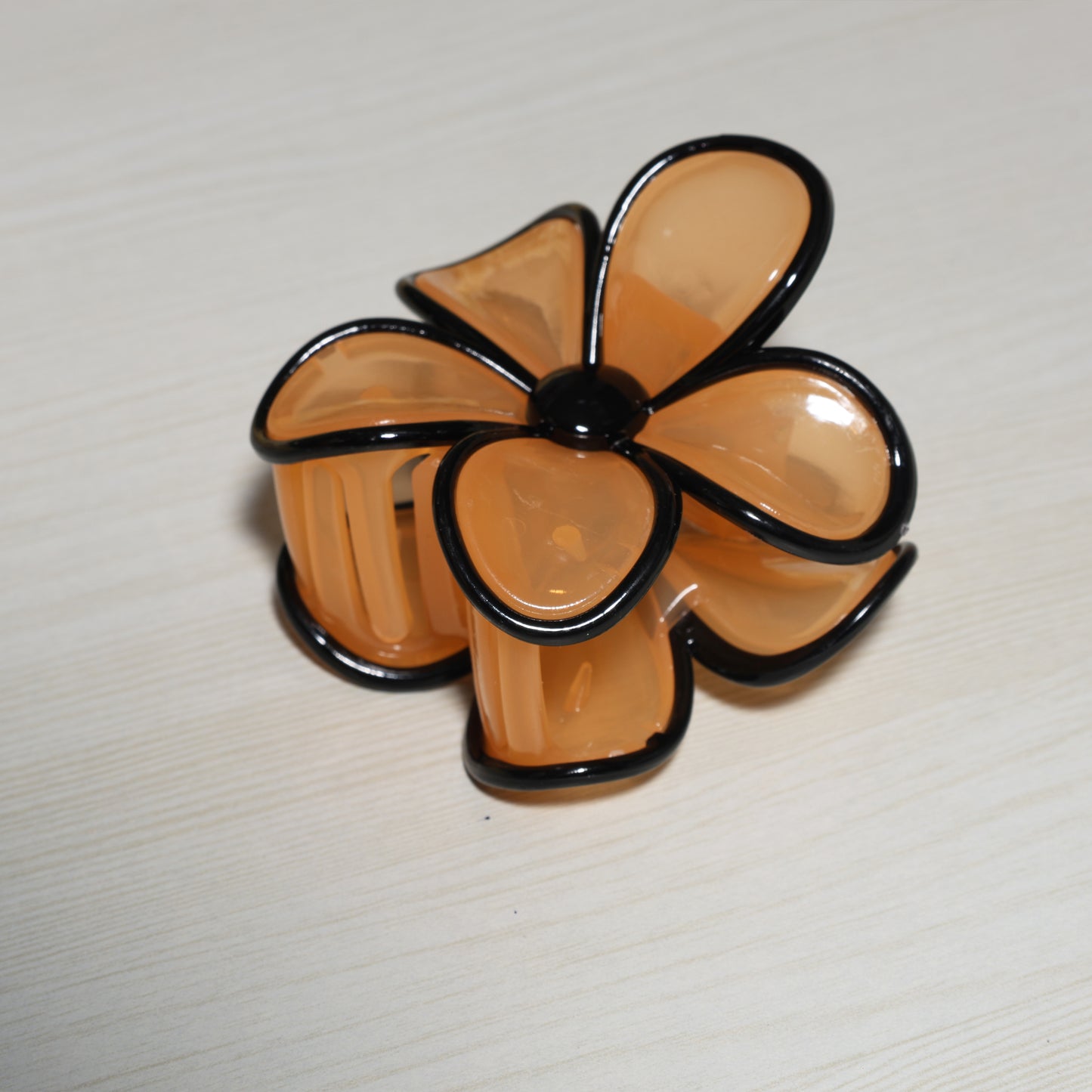 Pearl Finish Single Flower Clutch in translucent amber with black edges on a light surface