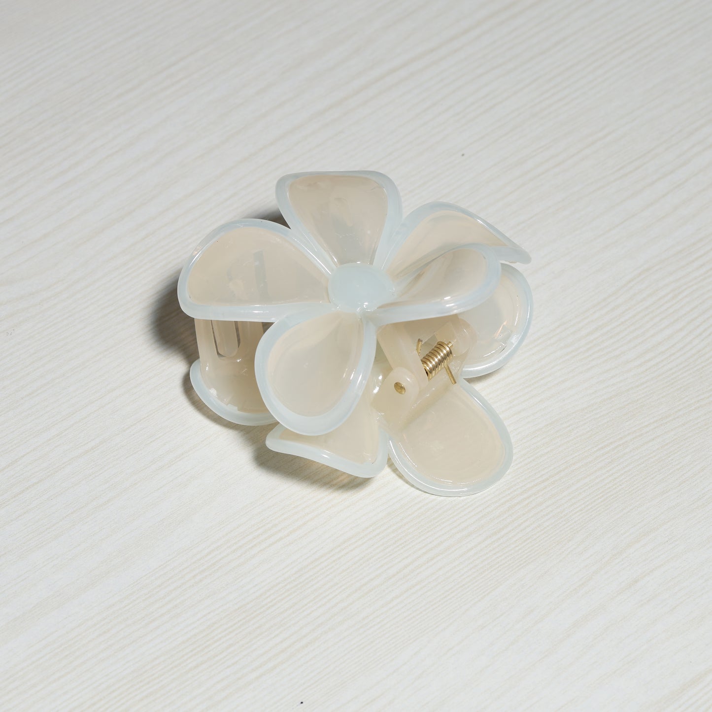 Pearl Finish Single Flower Clutch hair clip with translucent petals on light wood surface