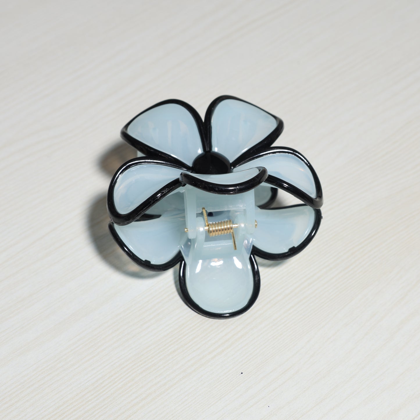 Pearl Finish Single Flower Clutch hair clip with black edges on light surface