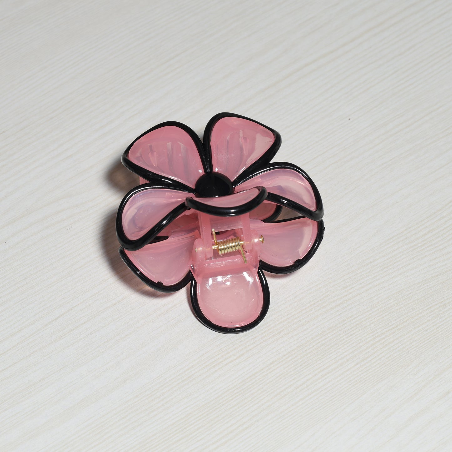Pearl Finish Single Flower Clutch in pink with black edges on a light wood surface