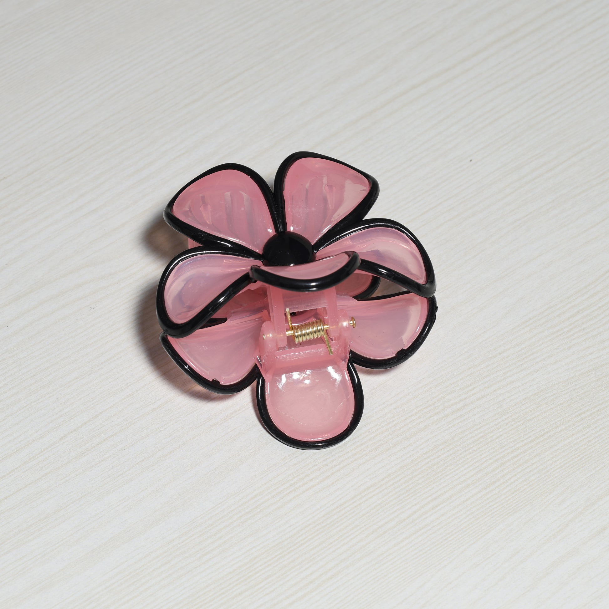 Pearl Finish Single Flower Clutch in pink with black edges on a light wood surface