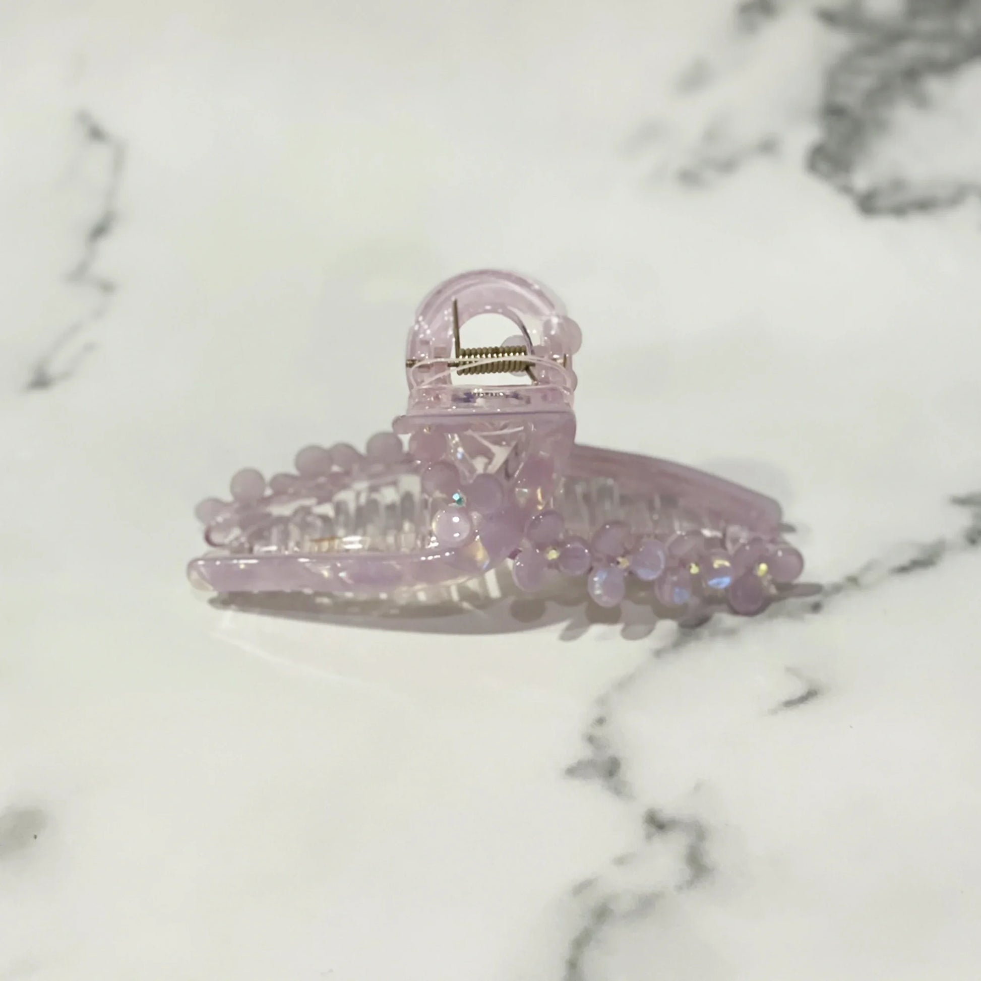 Light purple pearl floral hair clutches with decorative beads on a marble background