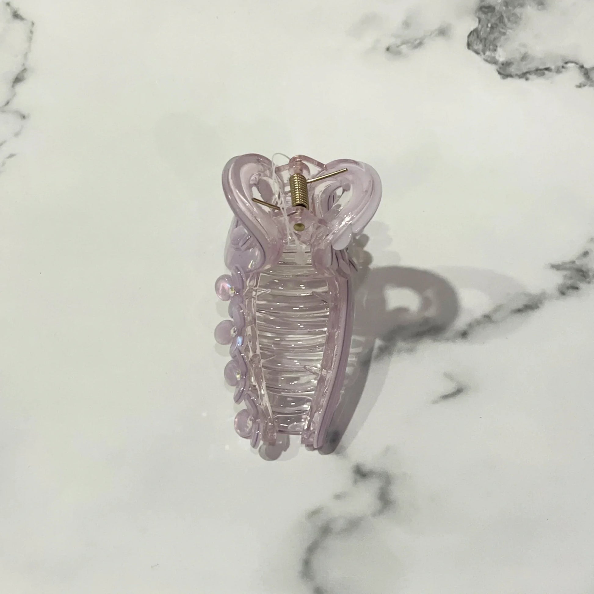 Light purple pearl floral hair clutches with a spring clasp on a white marble surface