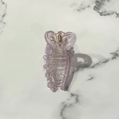 Light purple pearl floral hair clutches with a spring clasp on a white marble surface