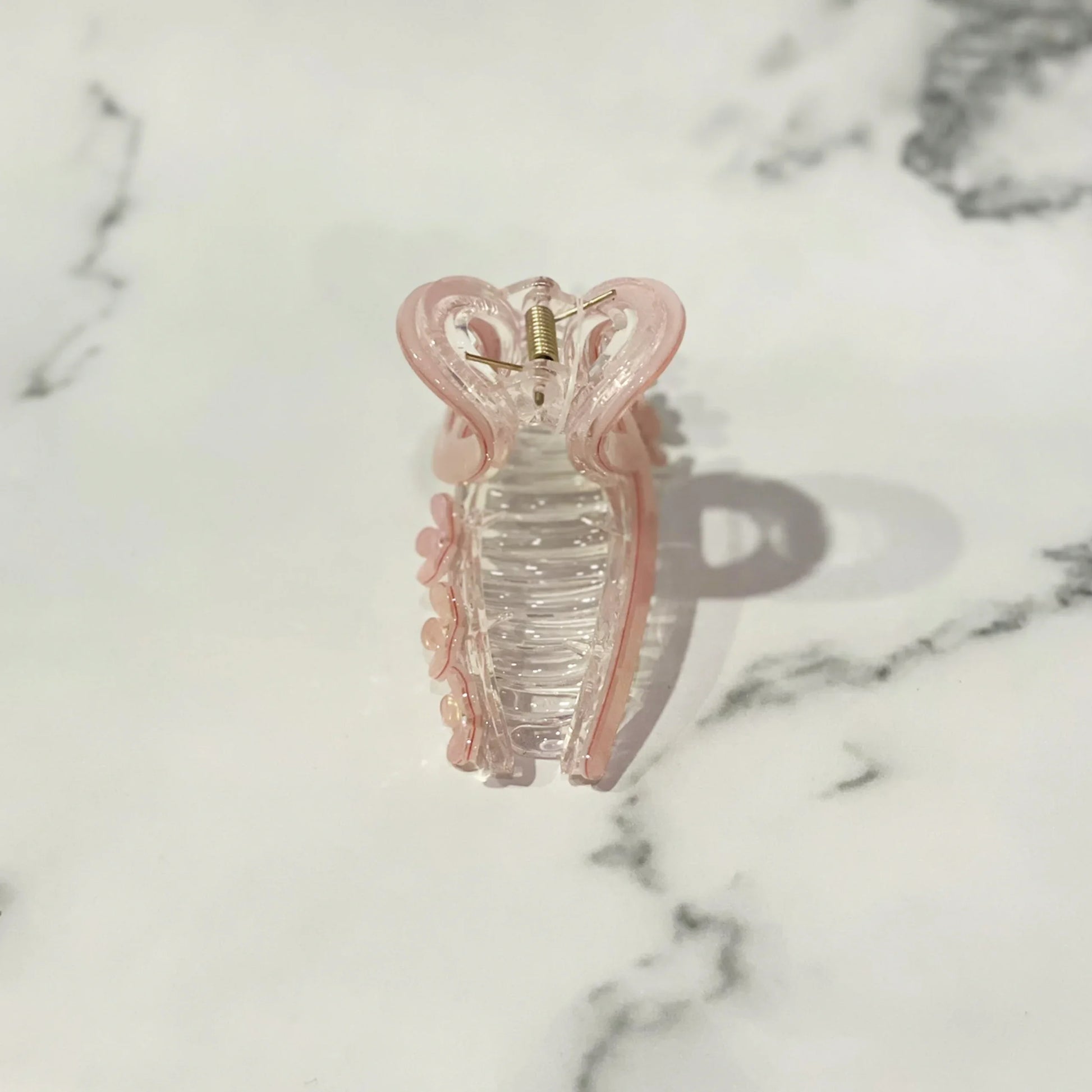 Pink translucent pearl floral hair clutches with a spring clasp on a marble background
