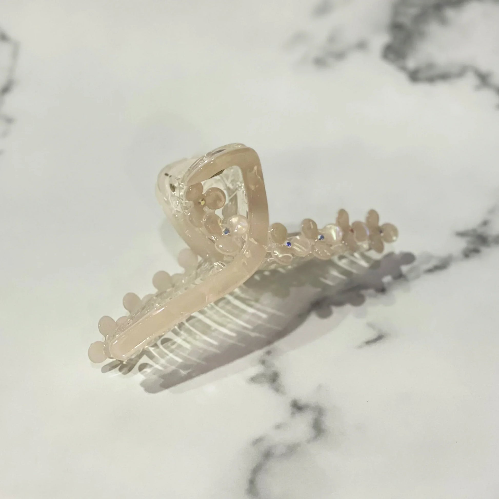 Beige pearl floral hair clutches with dainty flower details on a marble surface