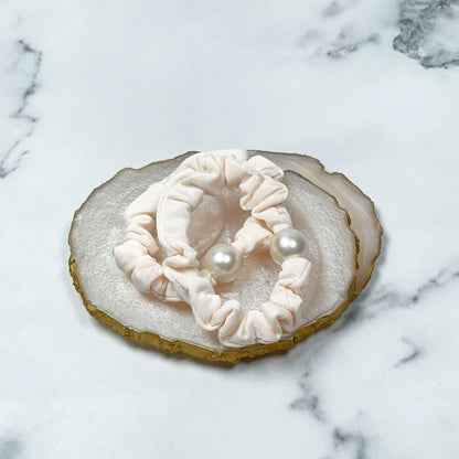 Cream fabric pearl hair ties with large white pearls placed on decorative agate slice