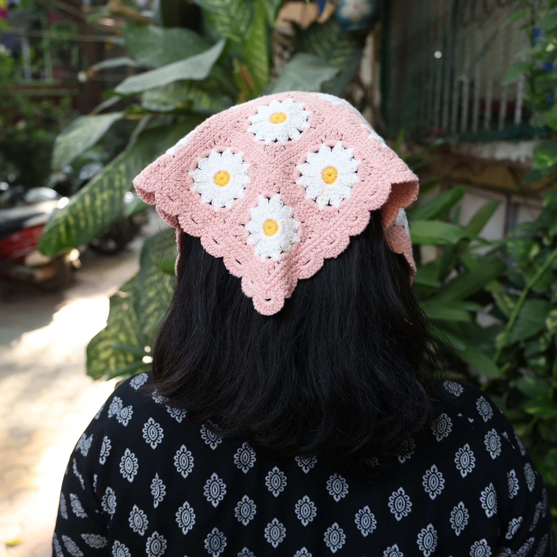 Bella Luxe pink crochet bandana with white and yellow floral patterns worn on dark hair