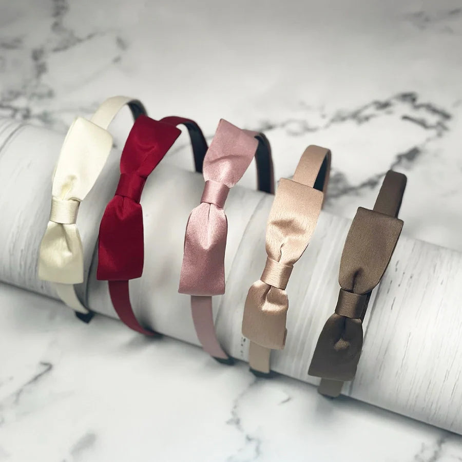 Set of satin bow hairbands in cream, red, pink, beige, and brown colors on marble background