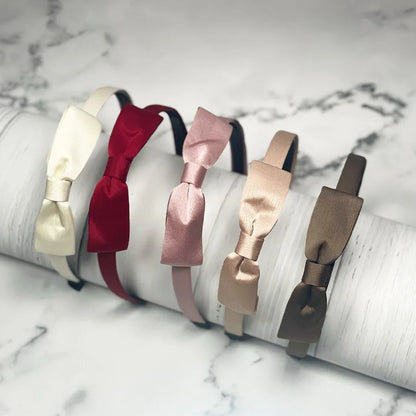 Set of satin bow hairbands in cream, red, pink, beige, and brown colors on marble background