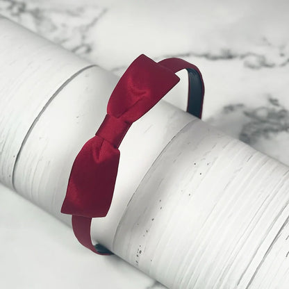 Elegant deep red satin bow hairbands with smooth finish on a slender headband
