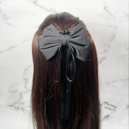 Black satin ribbon bow clips attached to long brown hair with decorative beads and hanging ribbons