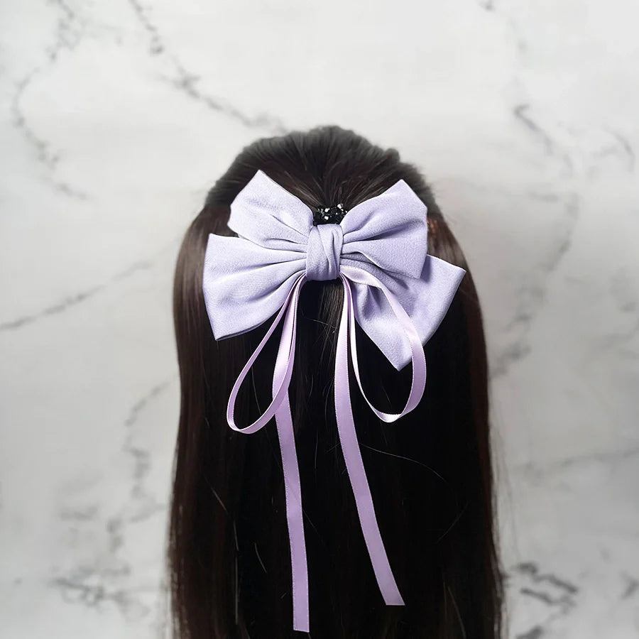 Light purple satin ribbon bow clips worn on dark brown hair with marble background