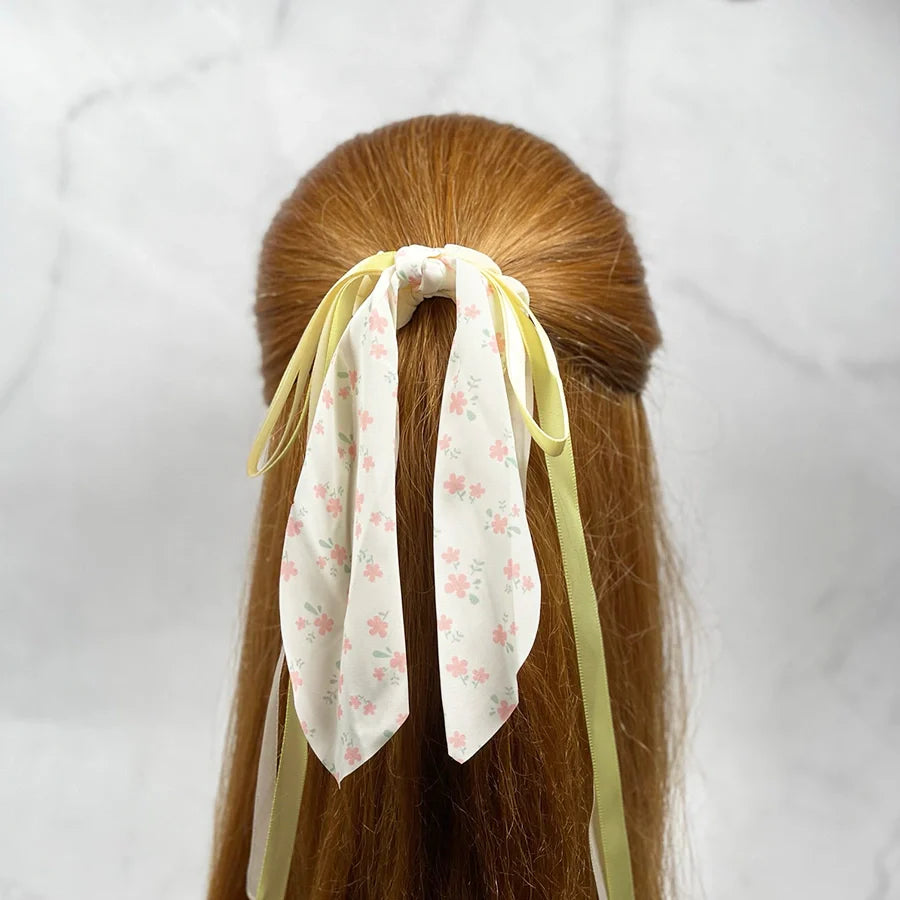 Scrunchies with ribbon for women featuring floral fabric and long pastel yellow ribbons on red hair