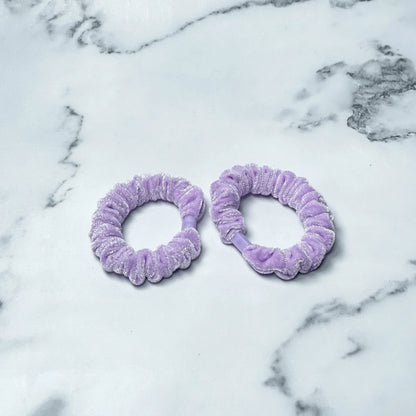 Two light purple shiny velvet hair ties on white marble surface from mydevelopmentstor