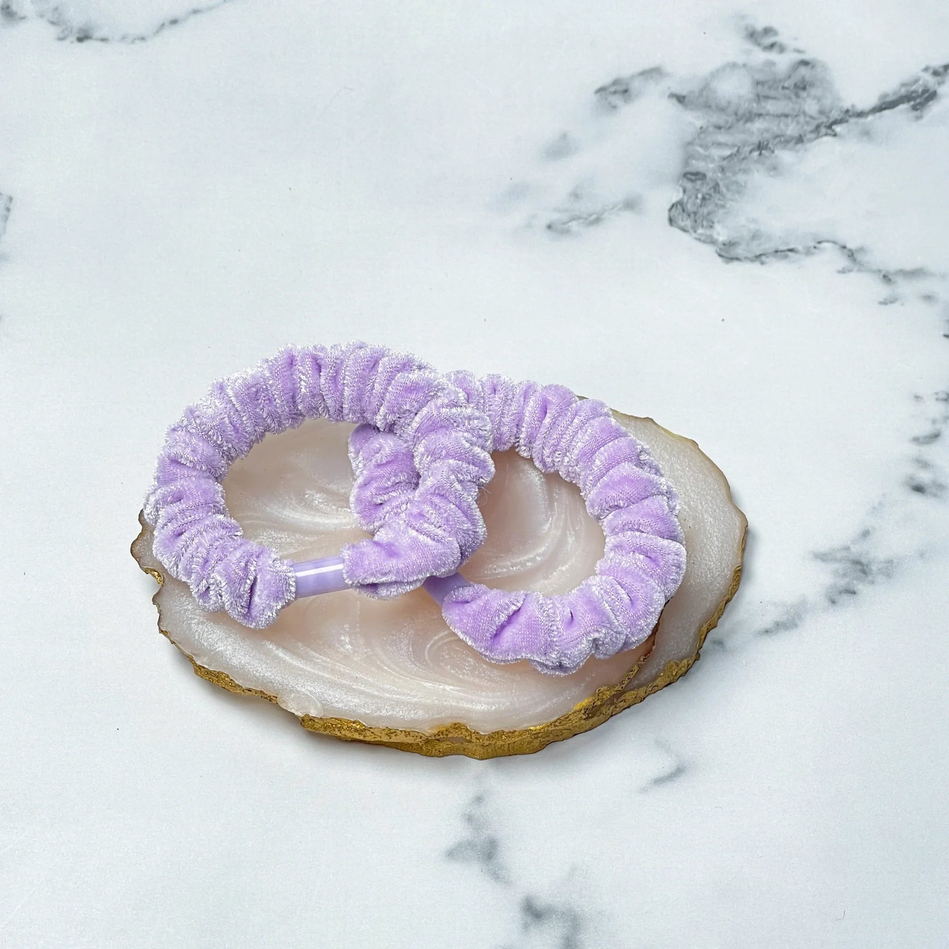 Lavender shiny velvet hair ties displayed on a polished agate stone with gold edges
