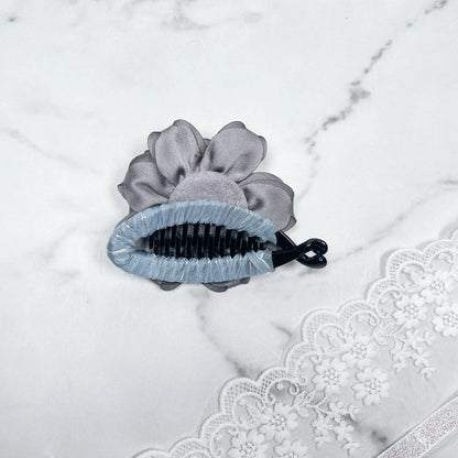 Bella Luxe silver crystal banana clip on marble surface with gray fabric flower and lace background