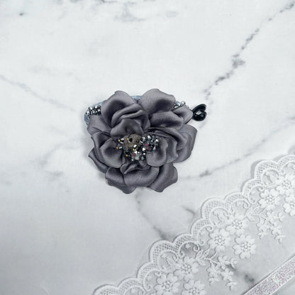 Bella Luxe silver crystal banana clip with gray fabric flower and decorative crystals on marble background
