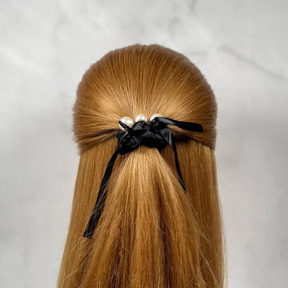Black soft cloth hair scrunchie with pearl accents securing long straight red hair